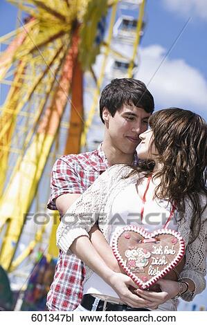 Stock Image - portrait of teenage couple at fun fair tenderly looking at each other. Fotosearch