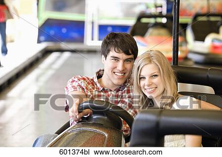 Stock Image - portrait of teenage couple sitting in bumper car. Fotosearch