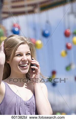 Stock Image - portrait of teenage girl talking on mobile phone at fun fair . Fotosearch