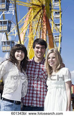 Stock Image - portrait of three teenagers on fun fair. Fotosearch