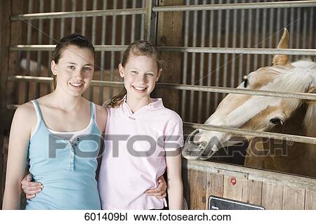portrait of two girls in stable at horse ranch View Large Photo Image Stock Image - portrait of two girls in stable at horse ranch. Fotosearch
