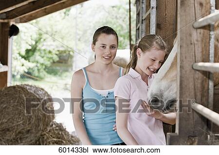 Stock Image - portrait of two girls in stable at horse ranch. Fotosearch