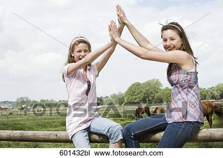 portrait of two girls sitting on fence at horse ranch View Large Photo Image Stock Image - portrait of two girls sitting on fence at horse ranch. Fotosearch