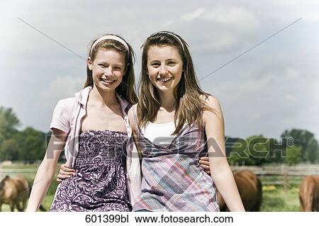 Stock Image - portrait of two girls together on horse ranch. Fotosearch