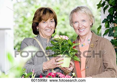 Stock Image - portrait of two senior woman buying flowers. Fotosearch