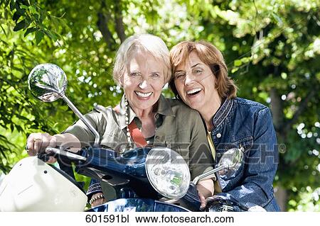 Stock Image - portrait of two senior woman sitting on scooter. Fotosearch