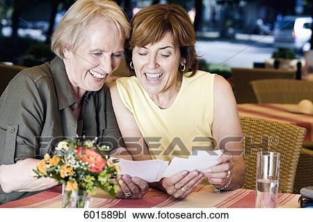 portrait of two senior women sitting in cafe looking at photographs View Large Photo Image Stock Image - portrait of two senior women sitting in cafe looking at photographs. Fotosearch