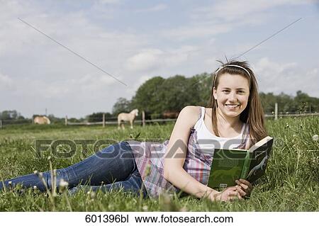 portrait of young girl lying in grass reading book View Large Photo Image Stock Image - portrait of young girl lying in grass reading book. Fotosearch
