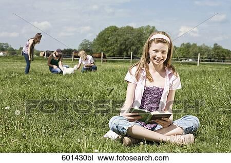 portrait of young girl lying in grass reading book View Large Photo Image Stock Image - portrait of young girl lying in grass reading book. Fotosearch