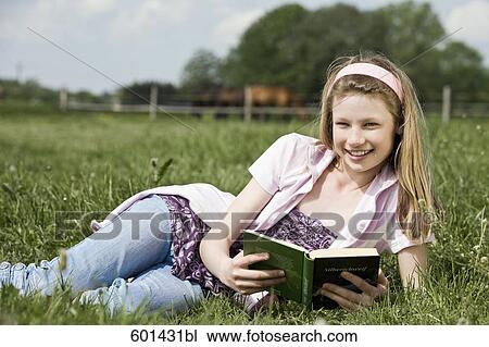 portrait of young girl lying in grass reading book View Large Photo Image Stock Image - portrait of young girl lying in grass reading book. Fotosearch