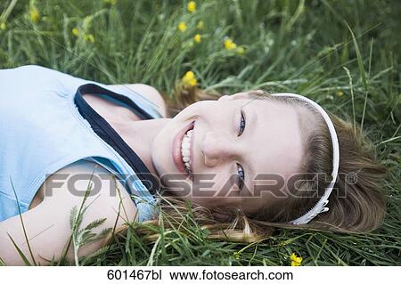 Stock Image - portrait of young girl lying in grass. Fotosearch
