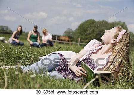 Stock Image - portrait of young girl lying in meadow enjoying the summer sun. Fotosearch