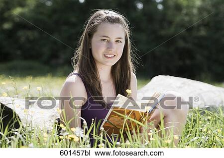 portrait of young girl sitting on tree trunk reading book View Large Photo Image Stock Image - portrait of young girl sitting on tree trunk reading book. Fotosearch