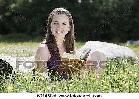 portrait of young girl sitting on tree trunk reading book View Large Photo Image Stock Image - portrait of young girl sitting on tree trunk reading book. Fotosearch