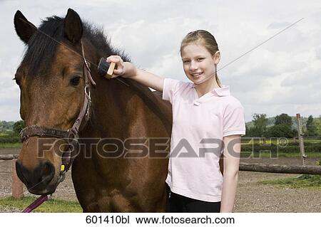 Stock Image - portrait of young girl with brown horse. Fotosearch