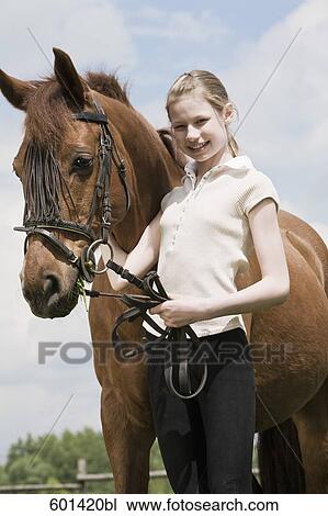 Stock Image - portrait of young girl with brown horse. Fotosearch