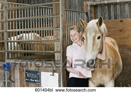 Stock Image - portrait of young girl with horse in stable. Fotosearch