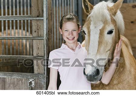 Stock Image - portrait of young girl with horse in stable. Fotosearch