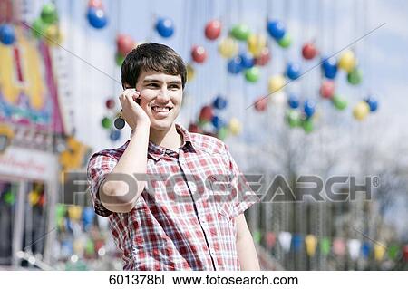 portrait of young man talking on mobile phone at fun fair View Large Photo Image Stock Image - portrait of young man talking on mobile phone at fun fair. Fotosearch