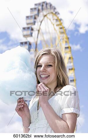 Stock Image - portrait of young womon eating cotton candy. Fotosearch