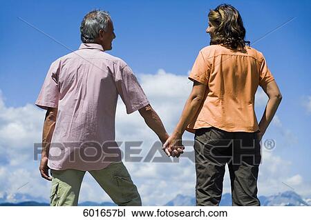 rear view of mature couple in the mountains holding hands View Large Photo Image Stock Image - rear view of mature couple in the mountains holding hands. Fotosearch