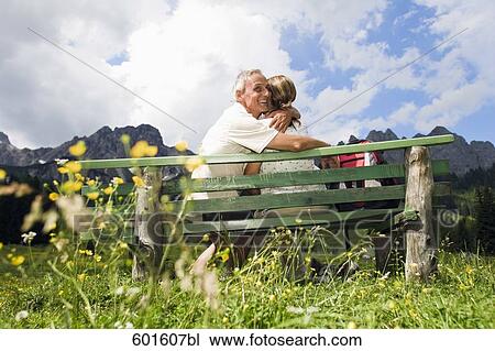 rear view of mature couple sitting on bench in front of mountains View Large Photo Image Stock Image - rear view of mature couple sitting on bench in front of mountains. Fotosearch