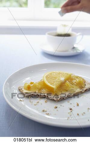 Stock Image - still life of crisp bread with orange jam and cup of tea. Fotosearch