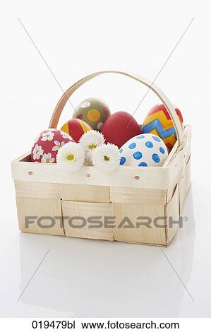 Stock Image - still life of painted eggs in wooden basket. Fotosearch