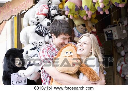 Stock Image - teenage couple at fun fair in close embrace. Fotosearch