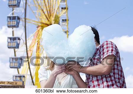 Stock Image - teenage couple sharing cotton candy at fun fair. Fotosearch