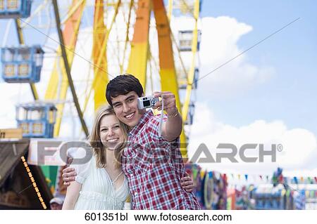 teenage couple taking photo of themselves at fun fair View Large Photo Image Stock Image - teenage couple taking photo of themselves at fun fair. Fotosearch