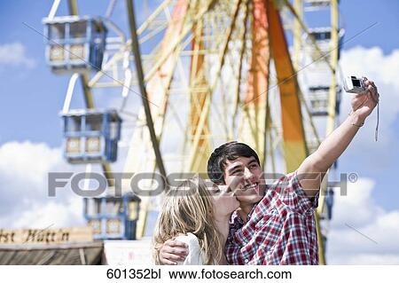 teenage couple taking photo of themselves at fun fair View Large Photo Image Stock Image - teenage couple taking photo of themselves at fun fair. Fotosearch