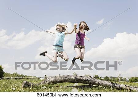 Stock Image - two girls jumping up in the air. Fotosearch