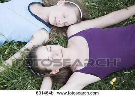 Stock Image - two girls lying in grass sleeping. Fotosearch