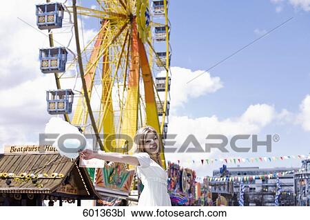 Stock Image - young woman at fun fair holding cotton candy. Fotosearch