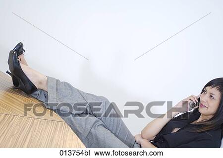 Stock Image - asian female executive talking on mobile in her office. Fotosearch