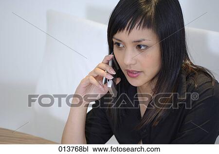 asian woman attentively listening to her mobile phone View Large Photo Image Stock Image - asian woman attentively listening to her mobile phone. Fotosearch