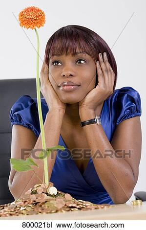 black woman looking at flower growing out of pile of coins View Large Photo Image Stock Image - black woman looking at flower growing out of pile of coins. Fotosearch