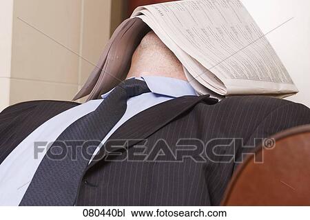 Stock Image - businessman dozing in hotel lobby with newspaper covering his face. Fotosearch