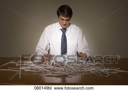 Stock Image - businessman having pile of shredded paper on his desk. Fotosearch