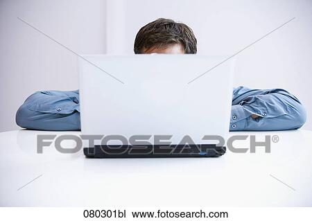 Stock Image - businessman hiding behind laptop computer. Fotosearch