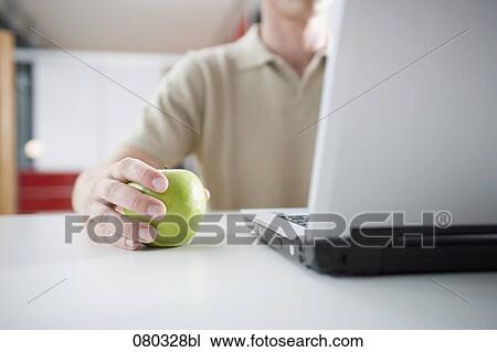businessman holding green apple while working on laptop computer View Large Photo Image Stock Image - businessman holding green apple while working on laptop computer. Fotosearch
