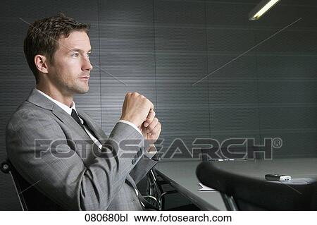 Stock Image - businessman sitting at conference table in meeting room. Fotosearch