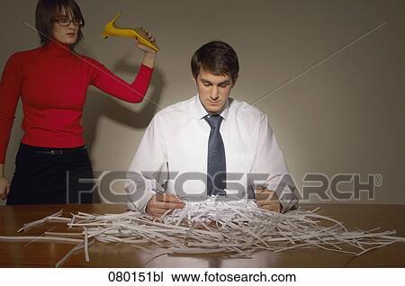 businessman sitting at desk full of shredded paper with female colleague trying to beat them with shoe View Large Photo Image Stock Image - businessman sitting at desk full of shredded paper with female colleague trying to beat them with shoe. Fotosearch