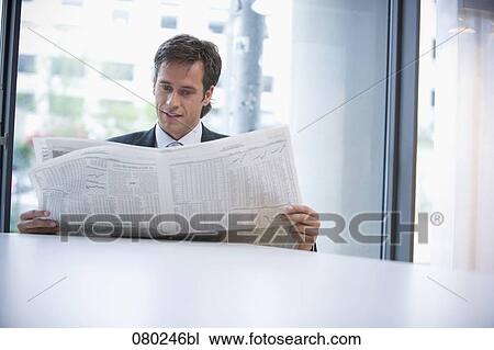 businessman sitting at desk reading stock market report in business paper View Large Photo Image Stock Image - businessman sitting at desk reading stock market report in business paper. Fotosearch