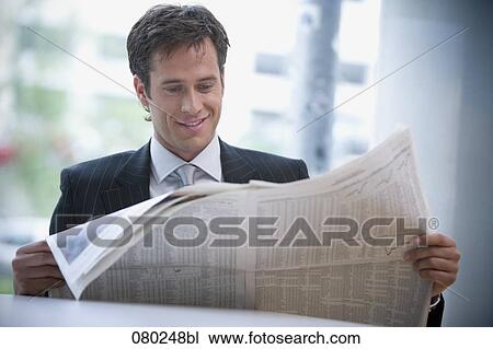 businessman sitting at desk reading stock market report in business paper View Large Photo Image Stock Image - businessman sitting at desk reading stock market report in business paper. Fotosearch