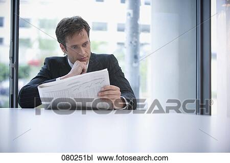 businessman sitting at desk reading stock market report in business paper View Large Photo Image Stock Image - businessman sitting at desk reading stock market report in business paper. Fotosearch