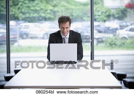 businessman sitting at table working with laptop computer View Large Photo Image Stock Image - businessman sitting at table working with laptop computer. Fotosearch