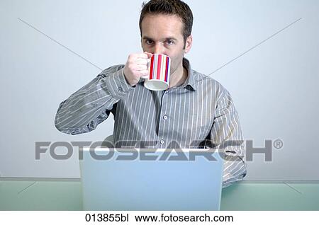 businessman sitting behind computer drinking some coffee View Large Photo Image Stock Image - businessman sitting behind computer drinking some coffee. Fotosearch