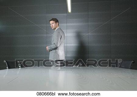Stock Image - businessman standing at conference table in meeting room. Fotosearch